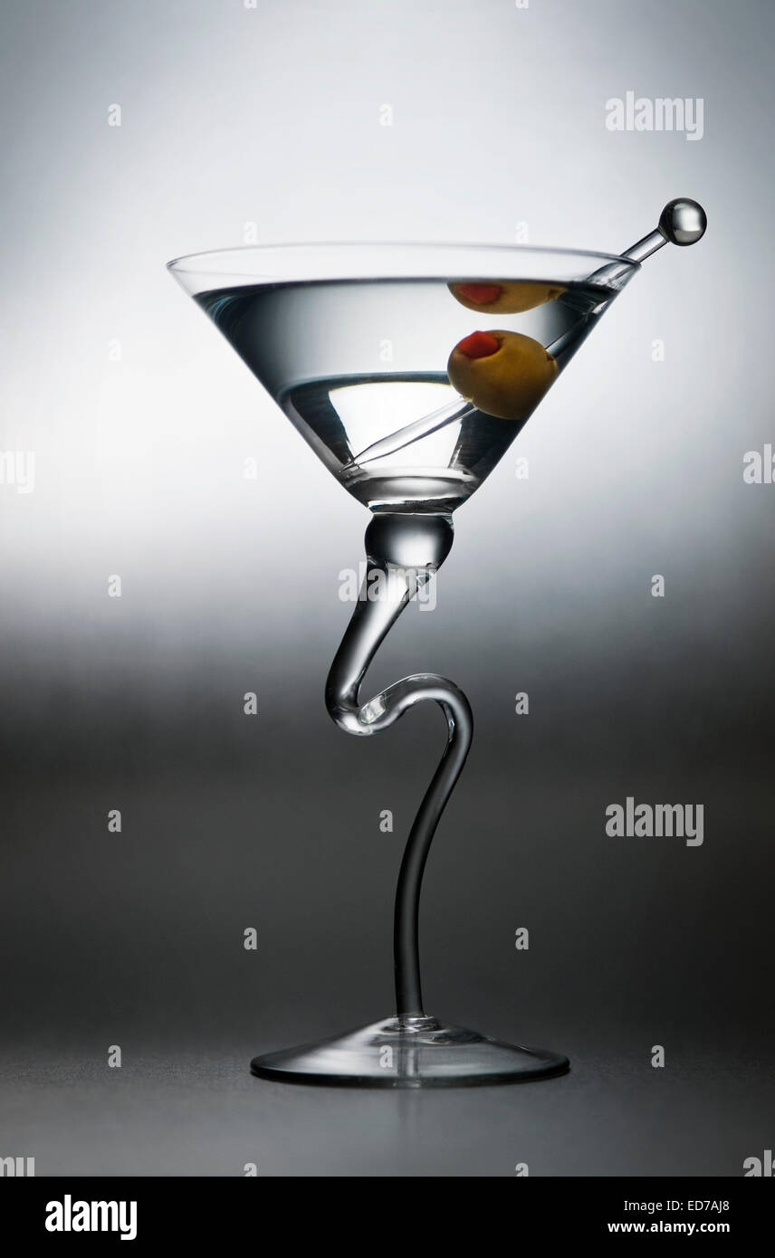 A contrasty modernistic martini cocktail alcoholic beverage with olive and glass pick Stock Photo