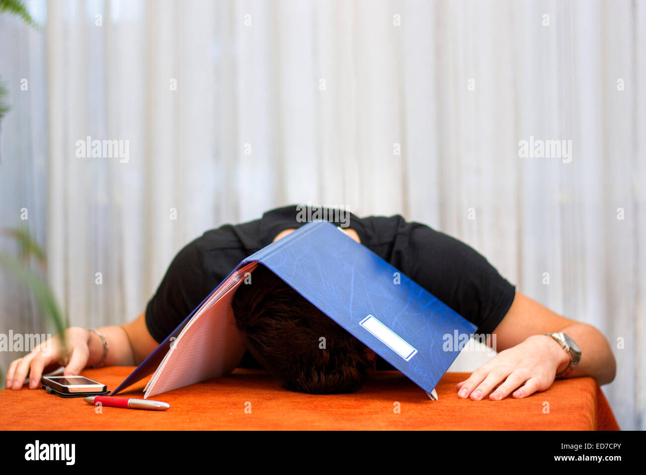 Tired, exhausted or despondent young man with a folder over his head Stock Photo