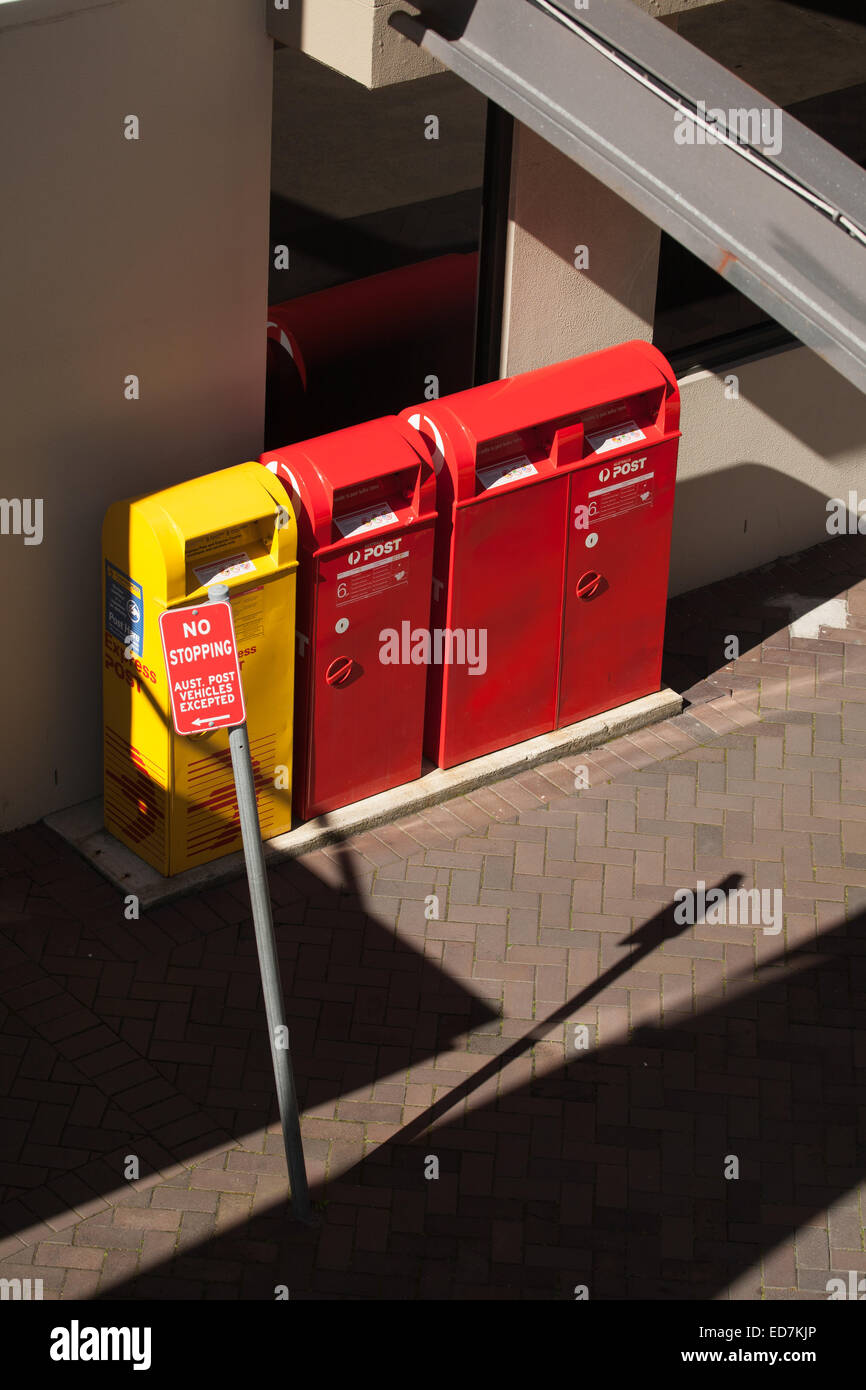 Yellow express and red regular Australia Post boxes on the footpath Newcastle NSW Australia Stock Photo
