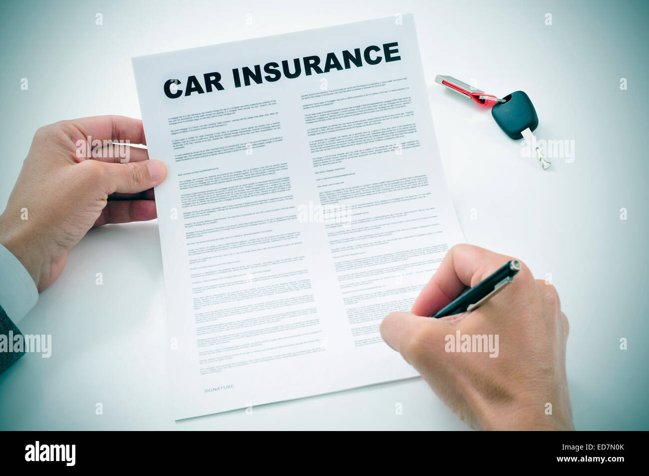 closeup of a young man signing a car insurance policy Stock Photo