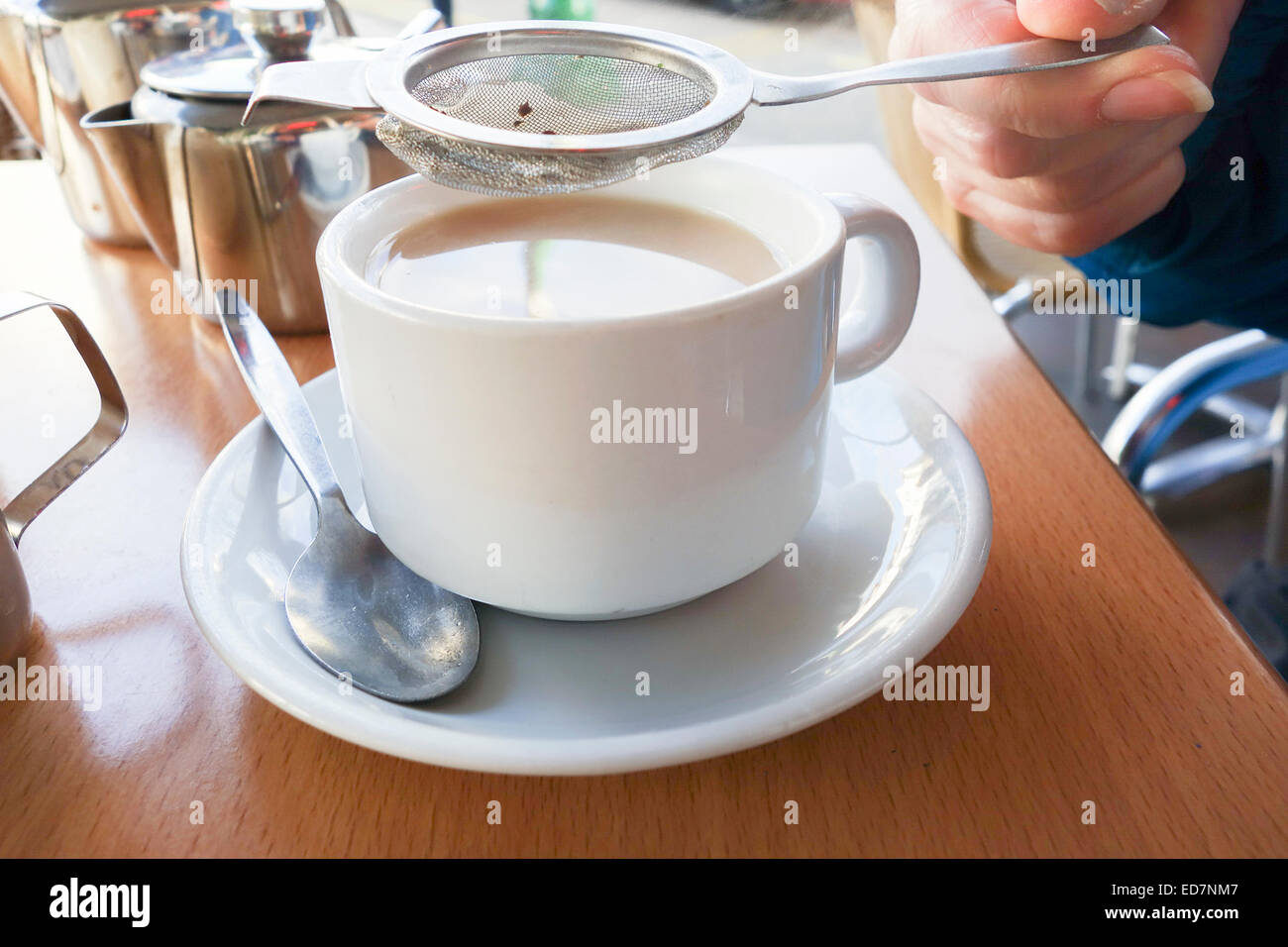 Cup of tea being poured using a tea strainer Stock Photo Alamy