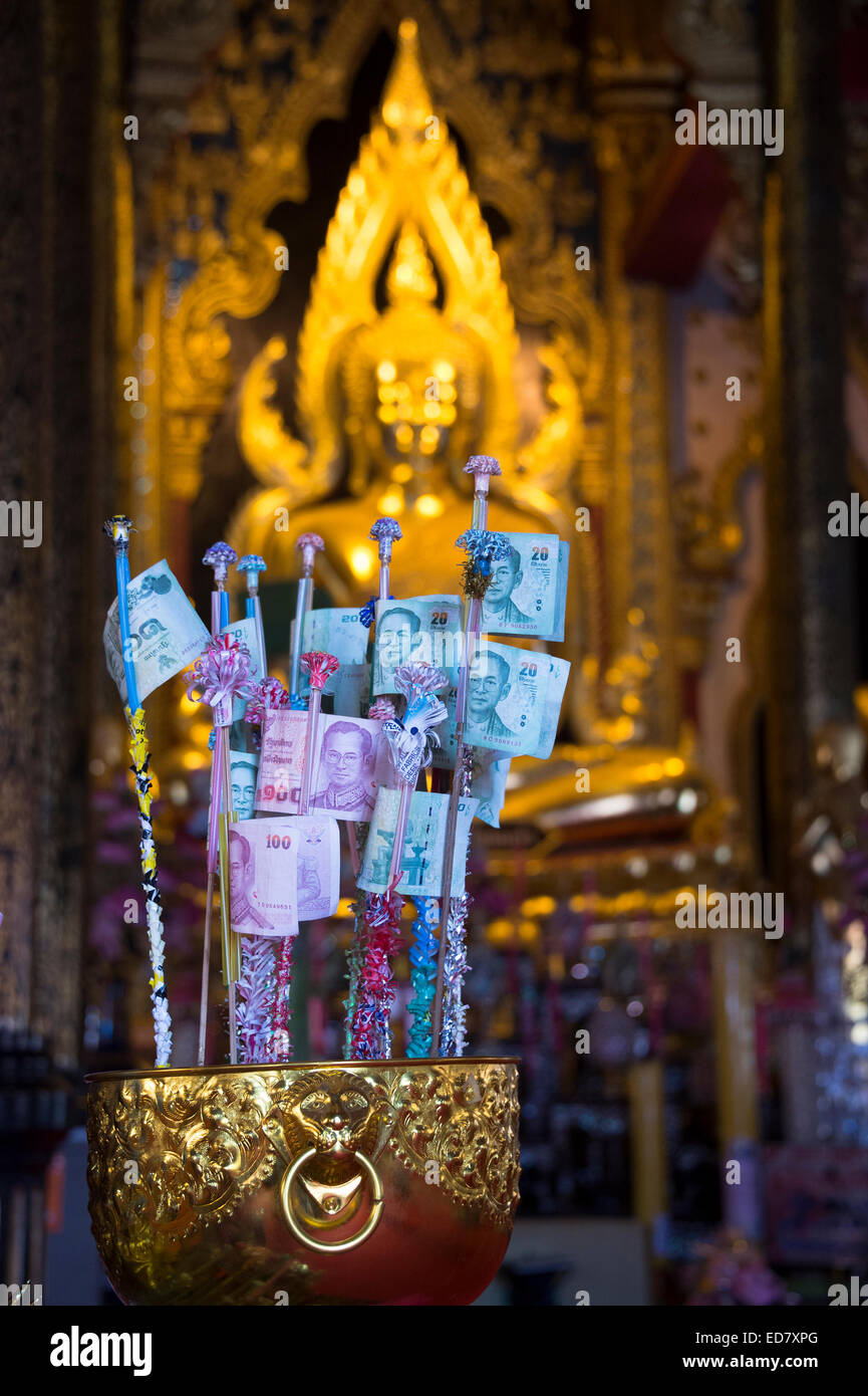 Thai Baht money offerings in front of a Buddha statue at a temple in Phitsanulok, Thailand Stock Photo