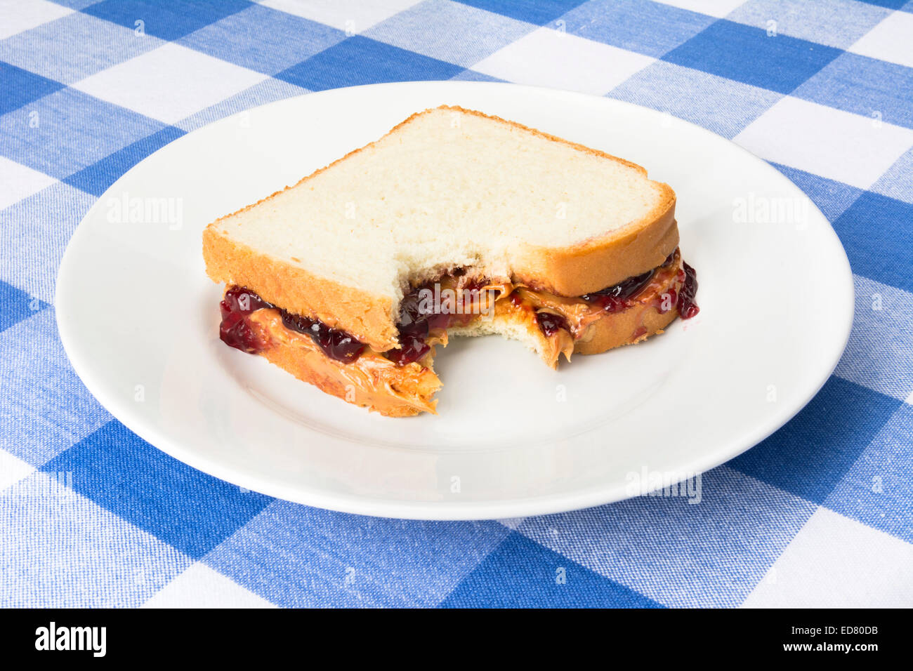 A delicious peanut butter and jelly sandwich with grape jam has a bite taken out of it during lunchtime. Stock Photo