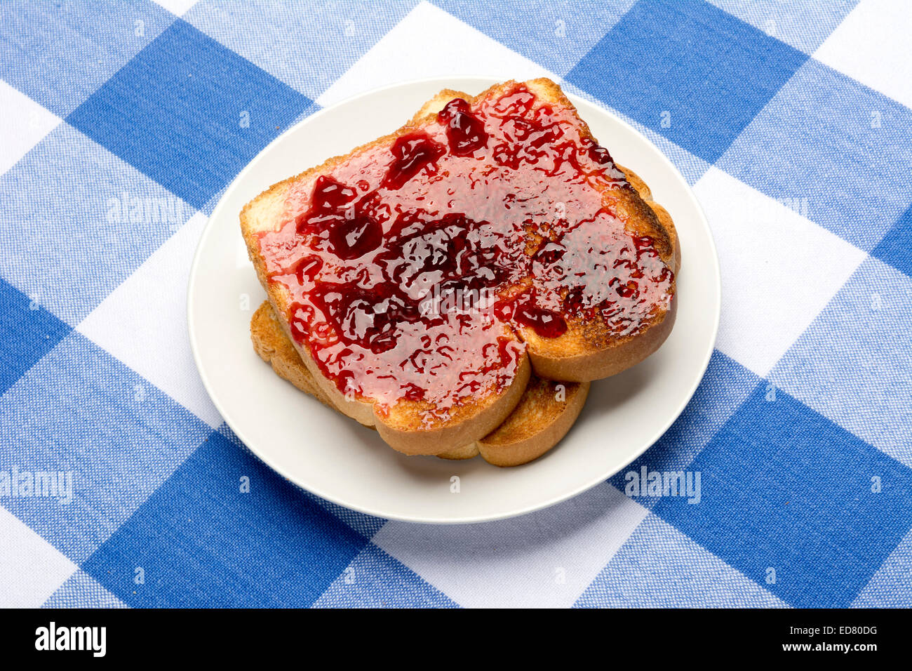 Fresh, hot toast spread with grape jelly sits during mealtime to be consumed. Stock Photo