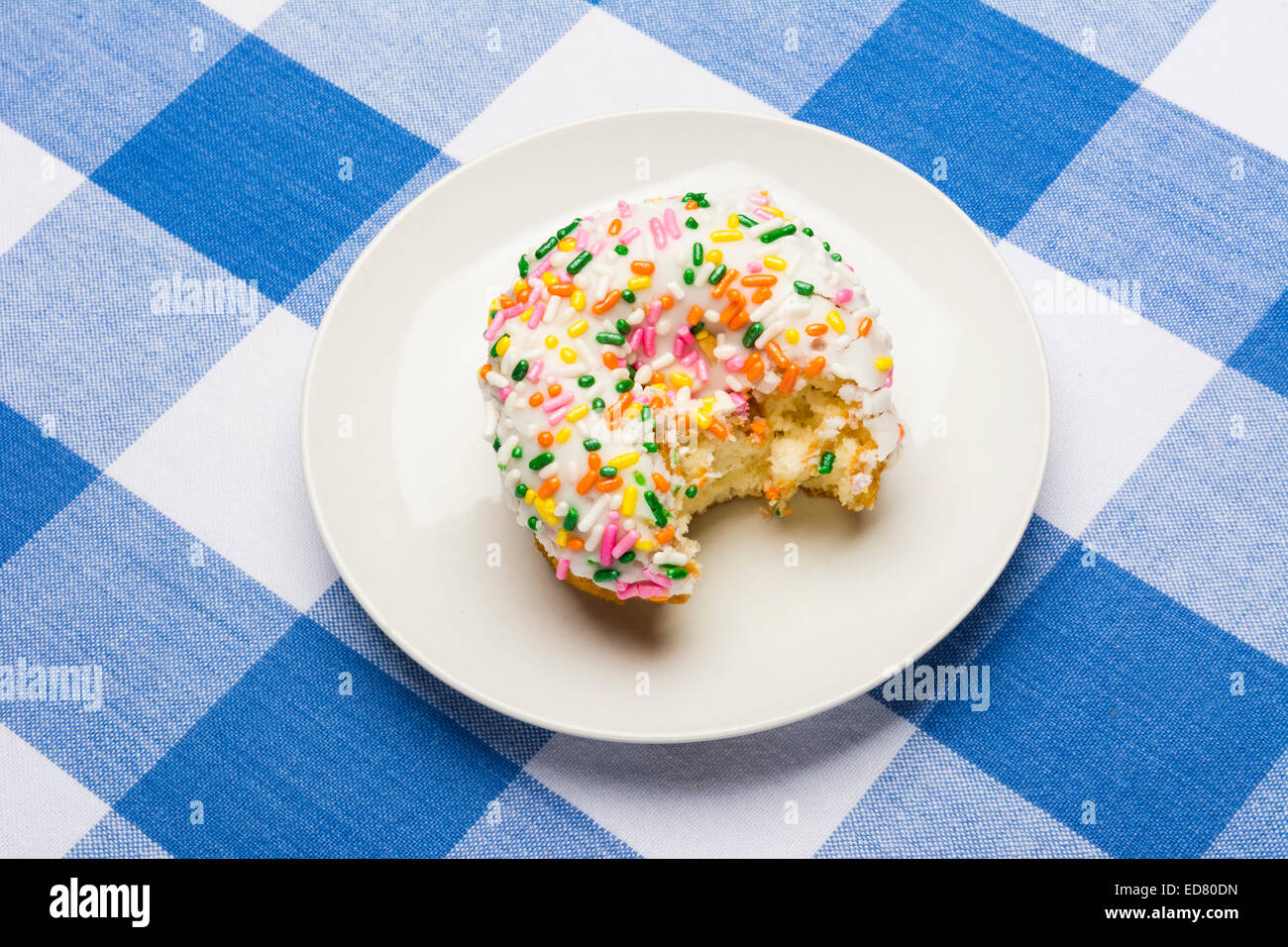 A freshly bitten, delicious icing coated cake donut with sweet