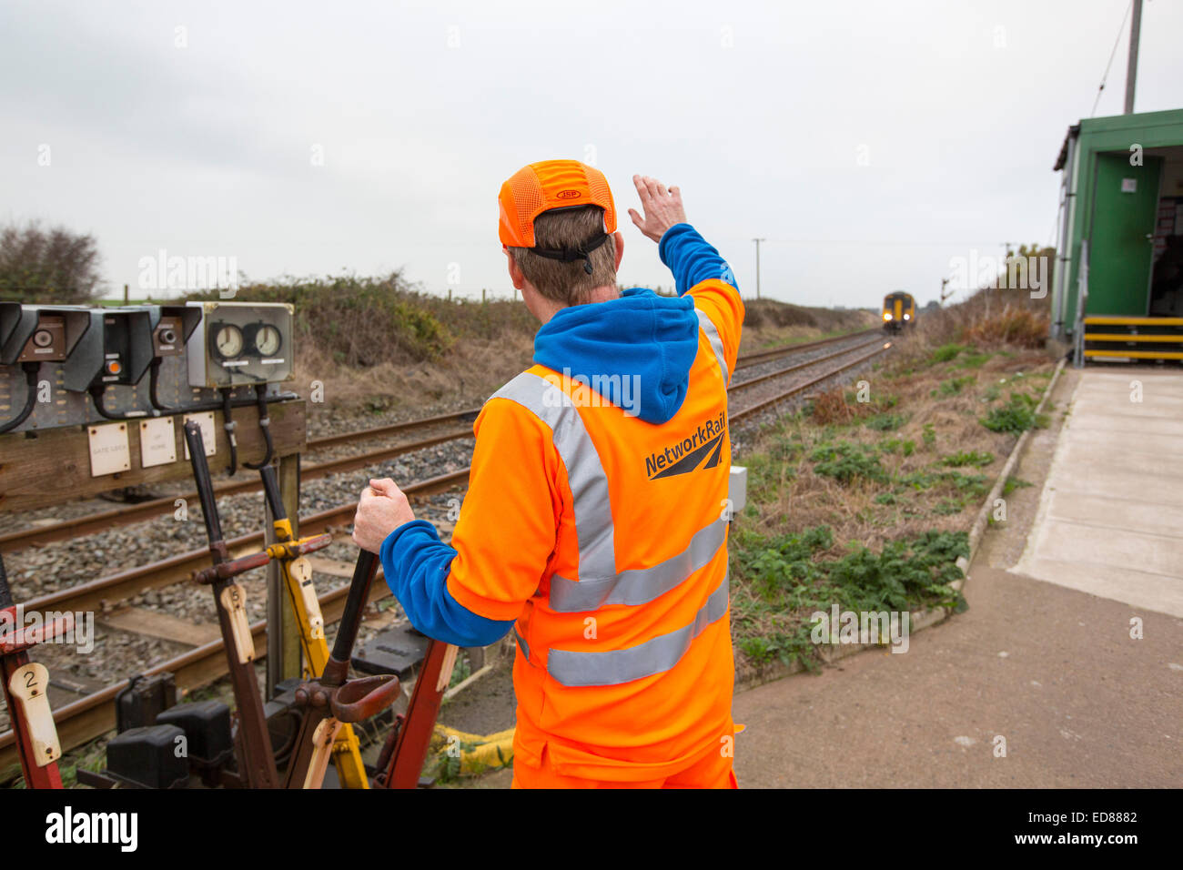 A man switching points at a level crossing near Haverigg, Cumbria, UK, as a train approaches. Stock Photo