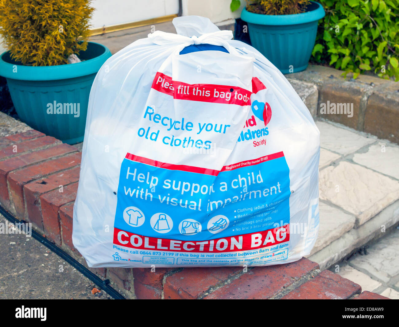 A Charity for visually impaired children bag filled with clothes placed outside a house ready for collection. Stock Photo