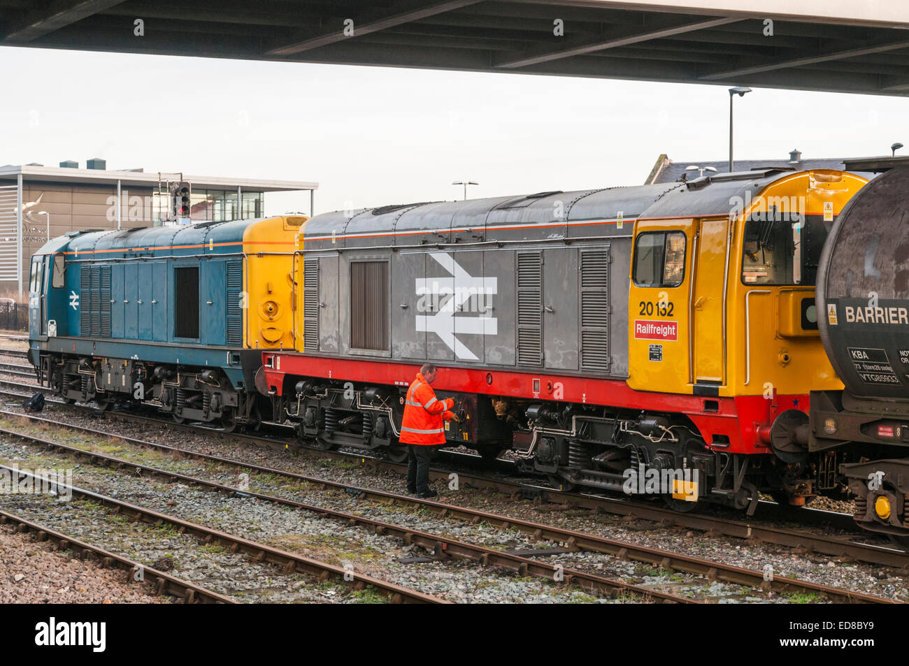 A train driver standing at the side of and checking a class 20 diesel ...