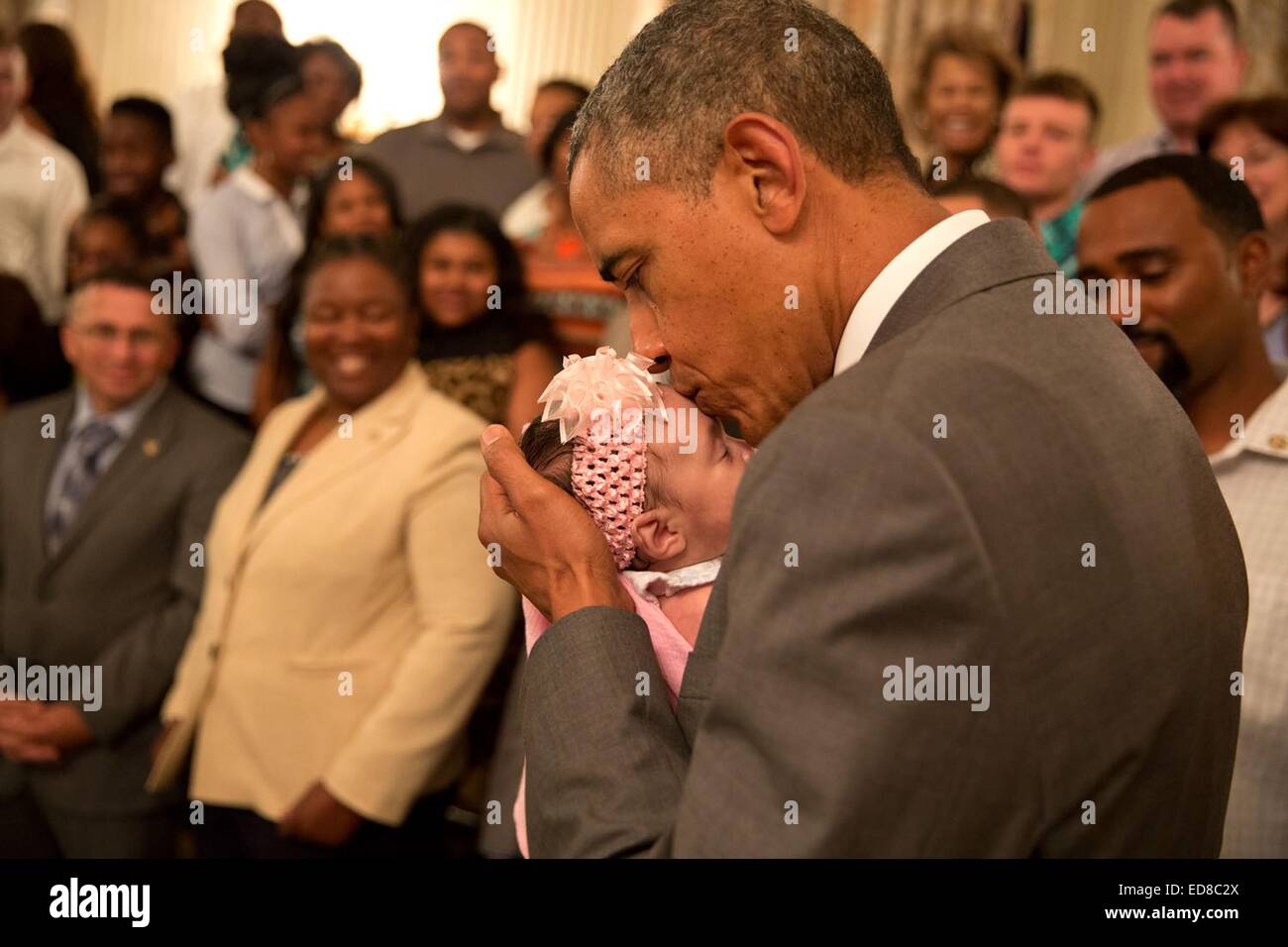 US President Barack Obama kisses a baby girl as he greeted wounded warriors and their families during their tour in the East Room of the White House June 23, 2014 in Washington, DC. Stock Photo
