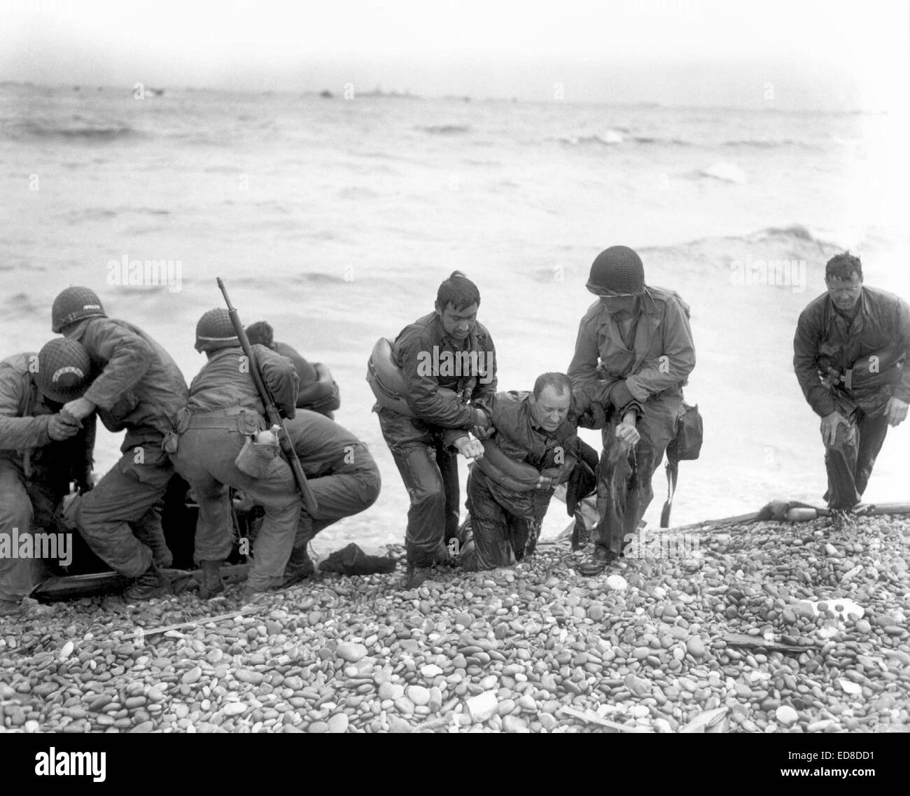 US soldiers help injured soldiers wade ashore onto Utah Beach during the D-Day invasion June 6, 1944 in Basse-Normandie, France. Stock Photo