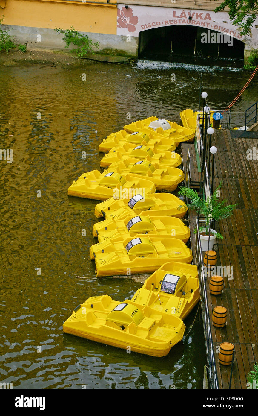A line of yellow pedal boats moored on the River Vltava in Prague