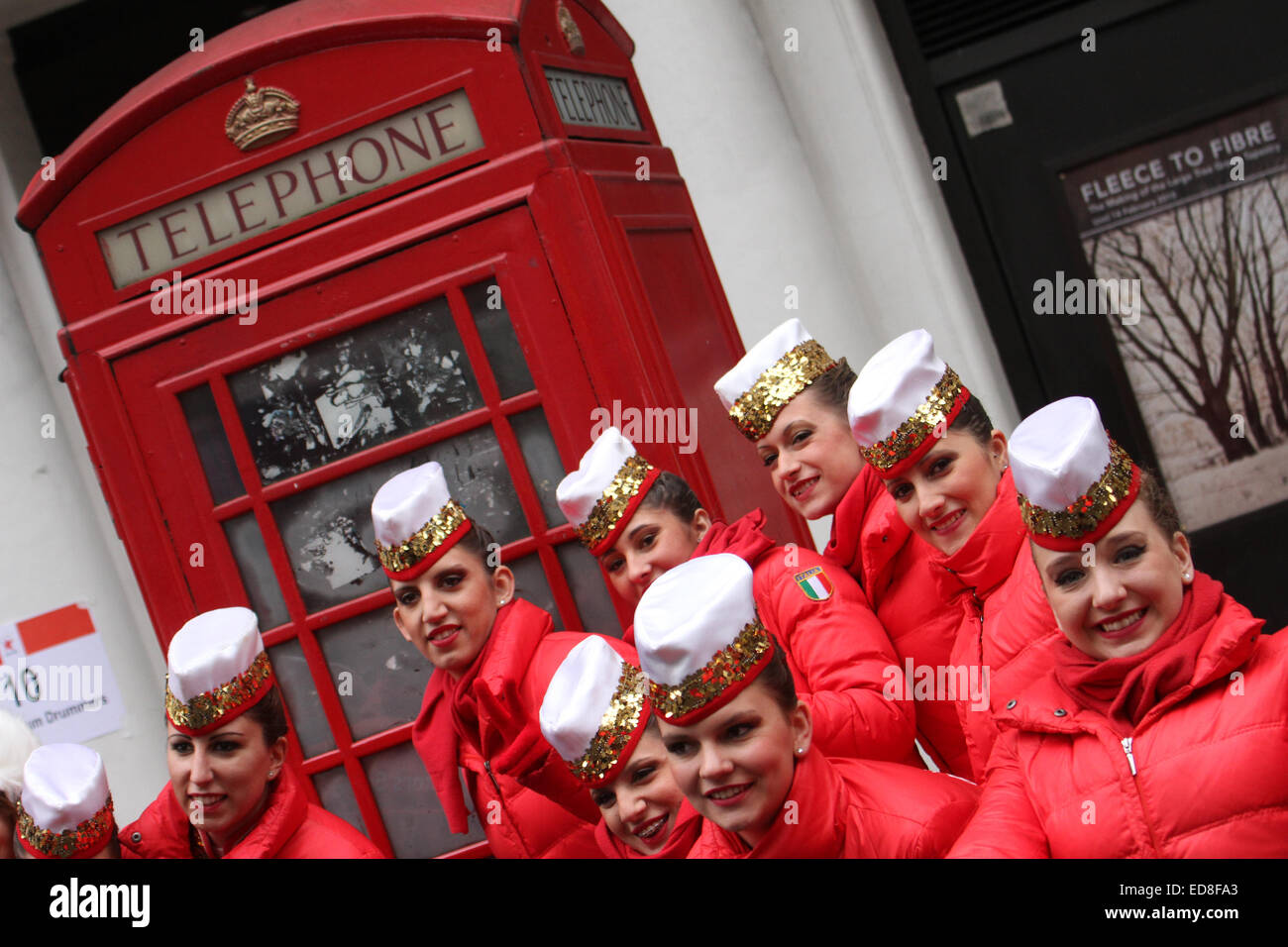 London, UK. 1 January 2015. The Majorettes 'Golden Stars Sobine' from Selci Italy pose for photos by a red London phone booth during a rehearsal for the annual London new years parade.Londoners and tourists turned up in droves for the new years parade. The annual parade goes through Picadilly, Regents street, Pall Mall and Whitehall a 2 mile route. Photo: David Mbiyu/ Alamy Live News Stock Photo