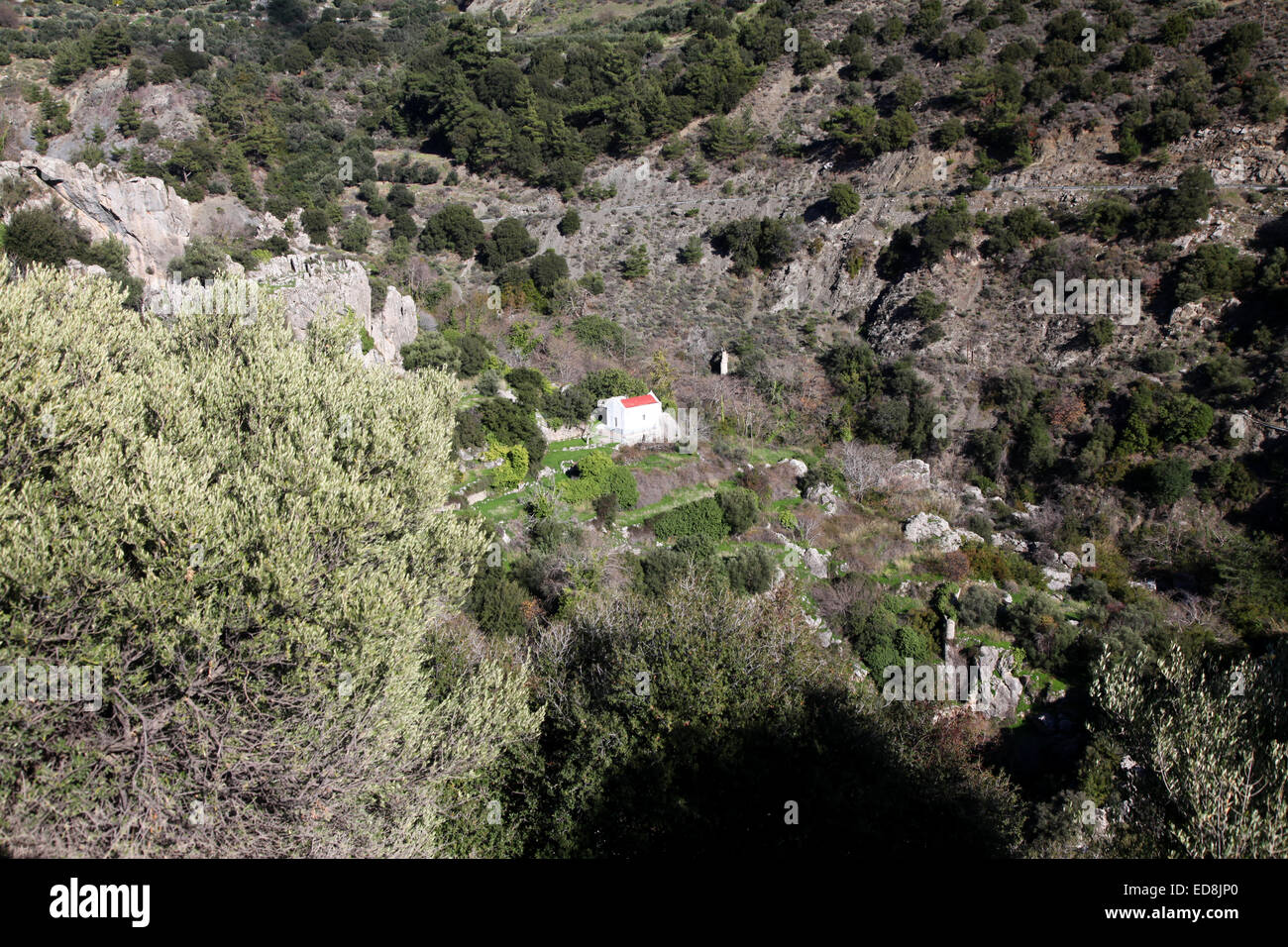 A small church nestles in a verdant Cretan valley high up in the mountains Stock Photo