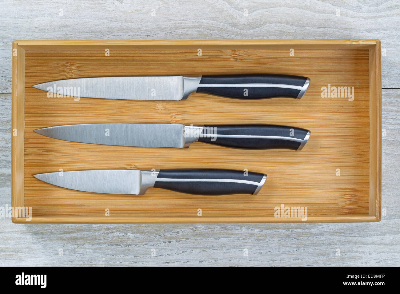 Close up horizontal image of a new wooden kitchen drawer with knife set resting on rustic white wood Stock Photo