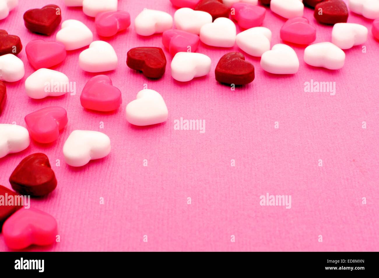 Valentines Day candy forming a border on a pink textured background Stock Photo