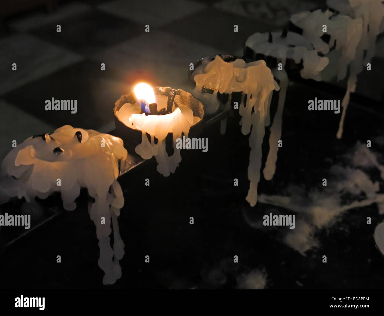 A single burning candle, in a church, wax dripping & melting Stock