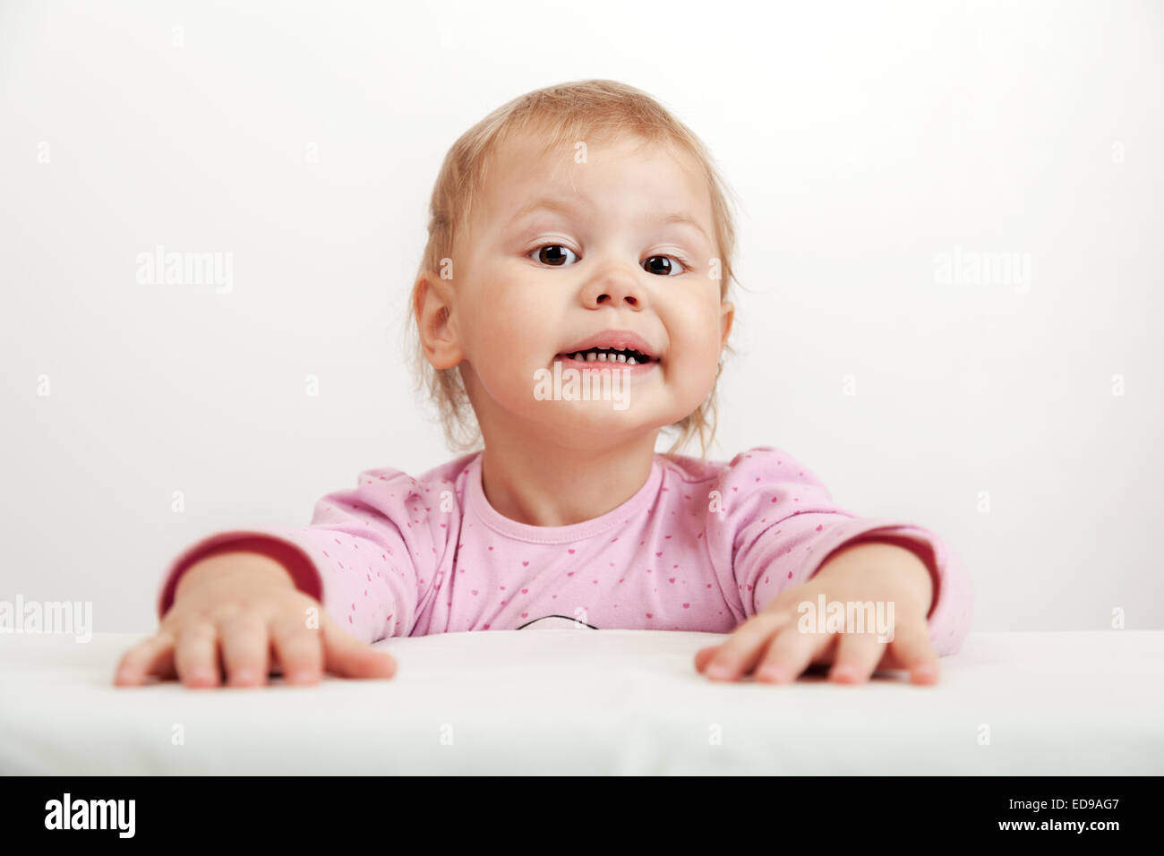 Funny Caucasian baby girl in pink on white background, closeup studio