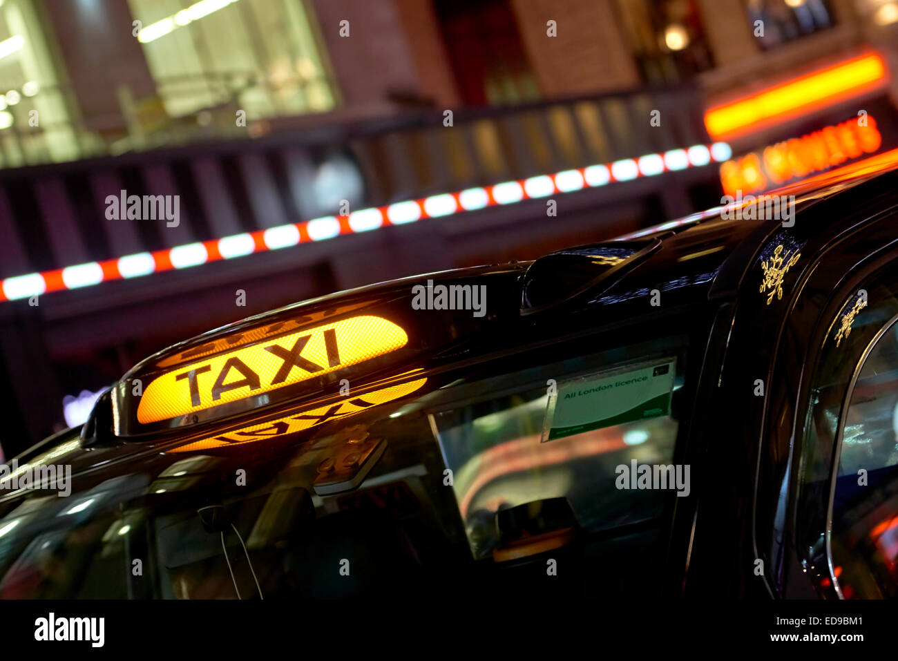 Low key detail of London black cab sign turned on at night, with shop ...