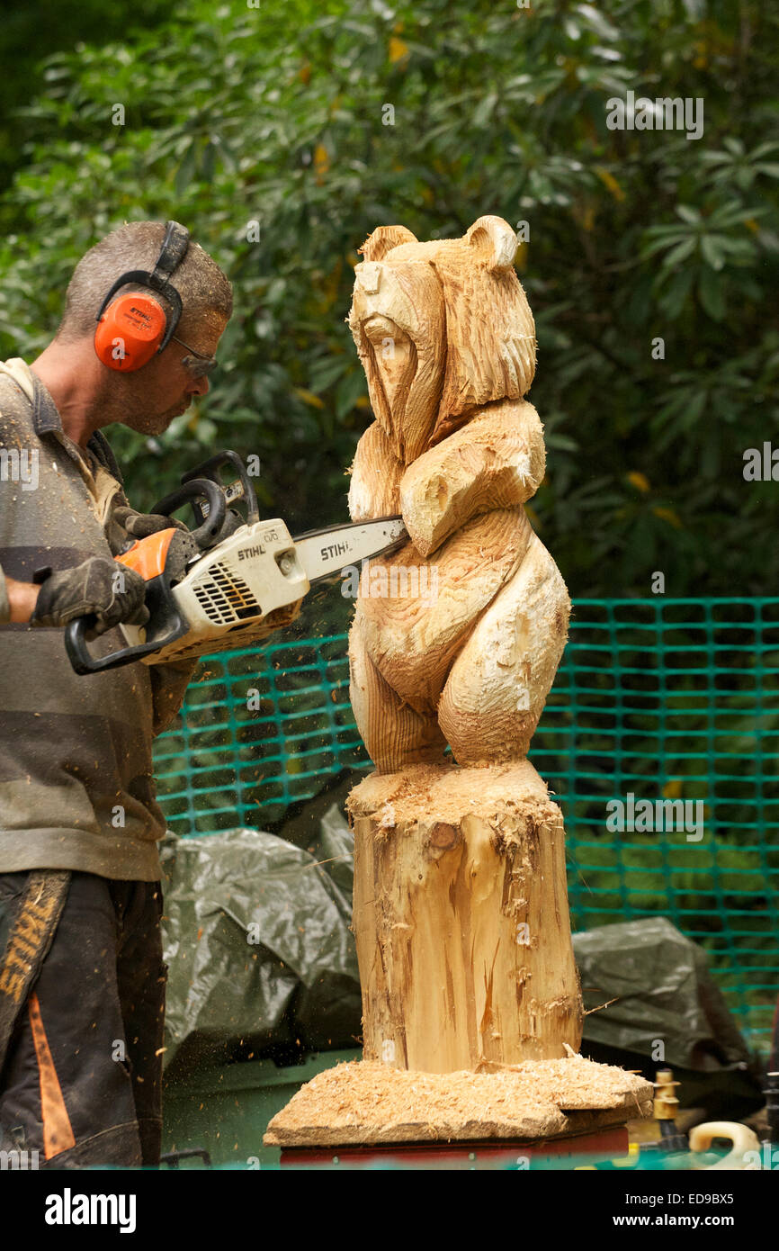 Wood carver carving a bear out of a tree trunk using a chainsaw Stock Photo