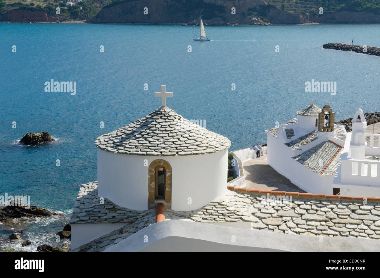 Churches and rooftops below the chora in Skopelos Town, Skopelos, Greek island. View out across the harbor and bay. October. Stock Photo