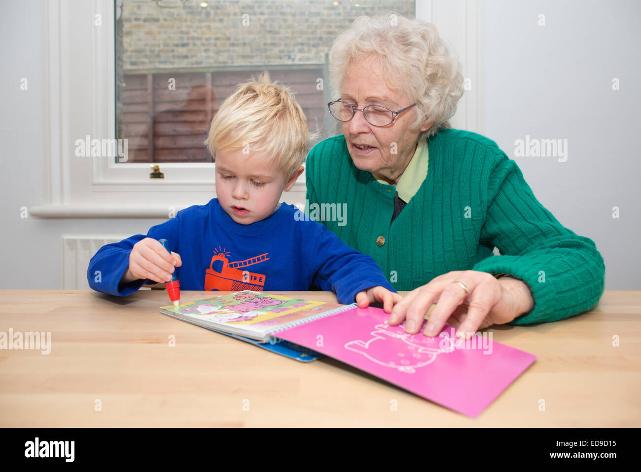 Elderly grandmother doing some book colouring exercises with her (4 year old) grandson Stock Photo