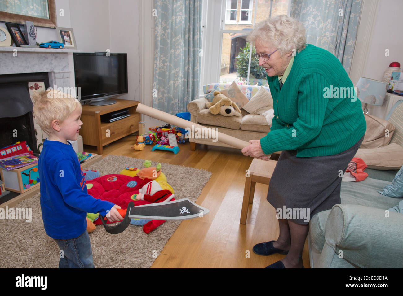 Elderly grandmother playing with her (4 year old) grandson in the living room Stock Photo