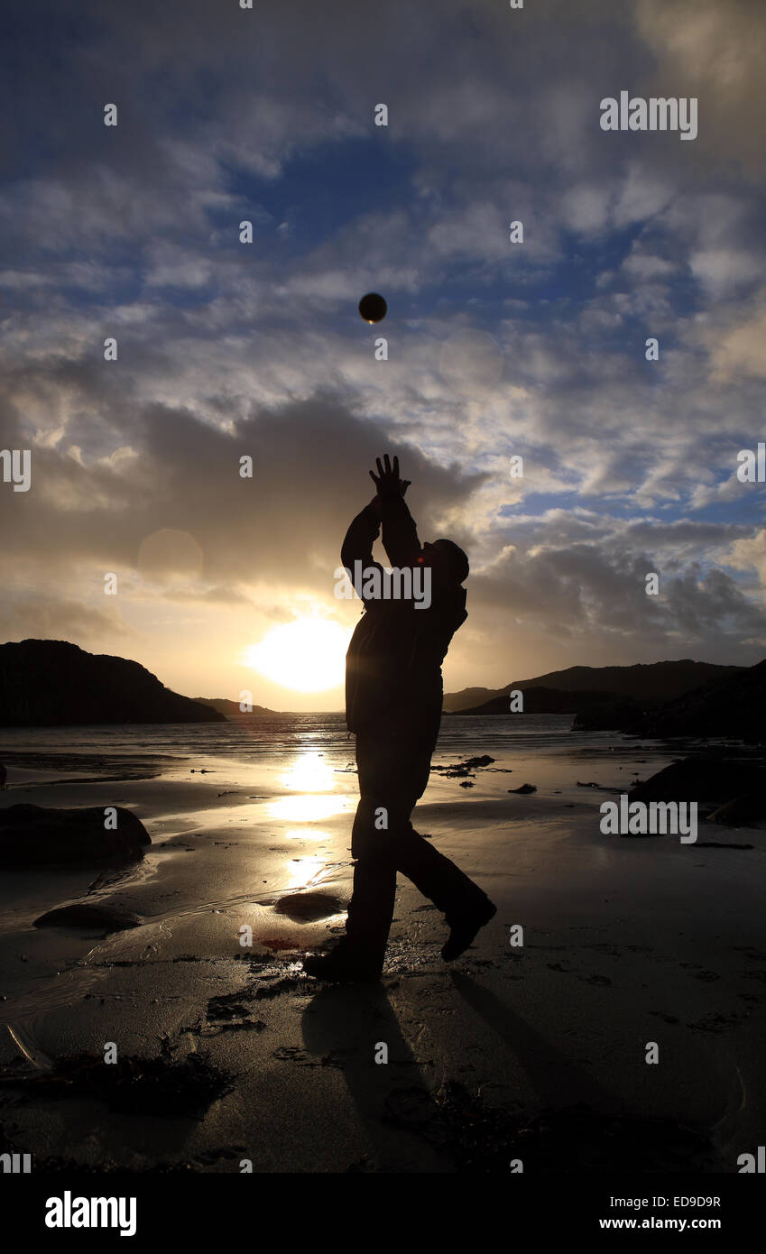 Knockvologan, Isle of Mull, Scotland. 2nd Jan, 2015. Extreme winds of the 2 January 2015 die down giving a short restbite to a beautiful sunset on Knockvologan beach on the Isle of Mull in Scotland's Inner Hebrides. A man takes advantage of the change of weather and gets some fresh air while throwing a ball about on the beach. Credit:  PictureScotland/Alamy Live News Stock Photo