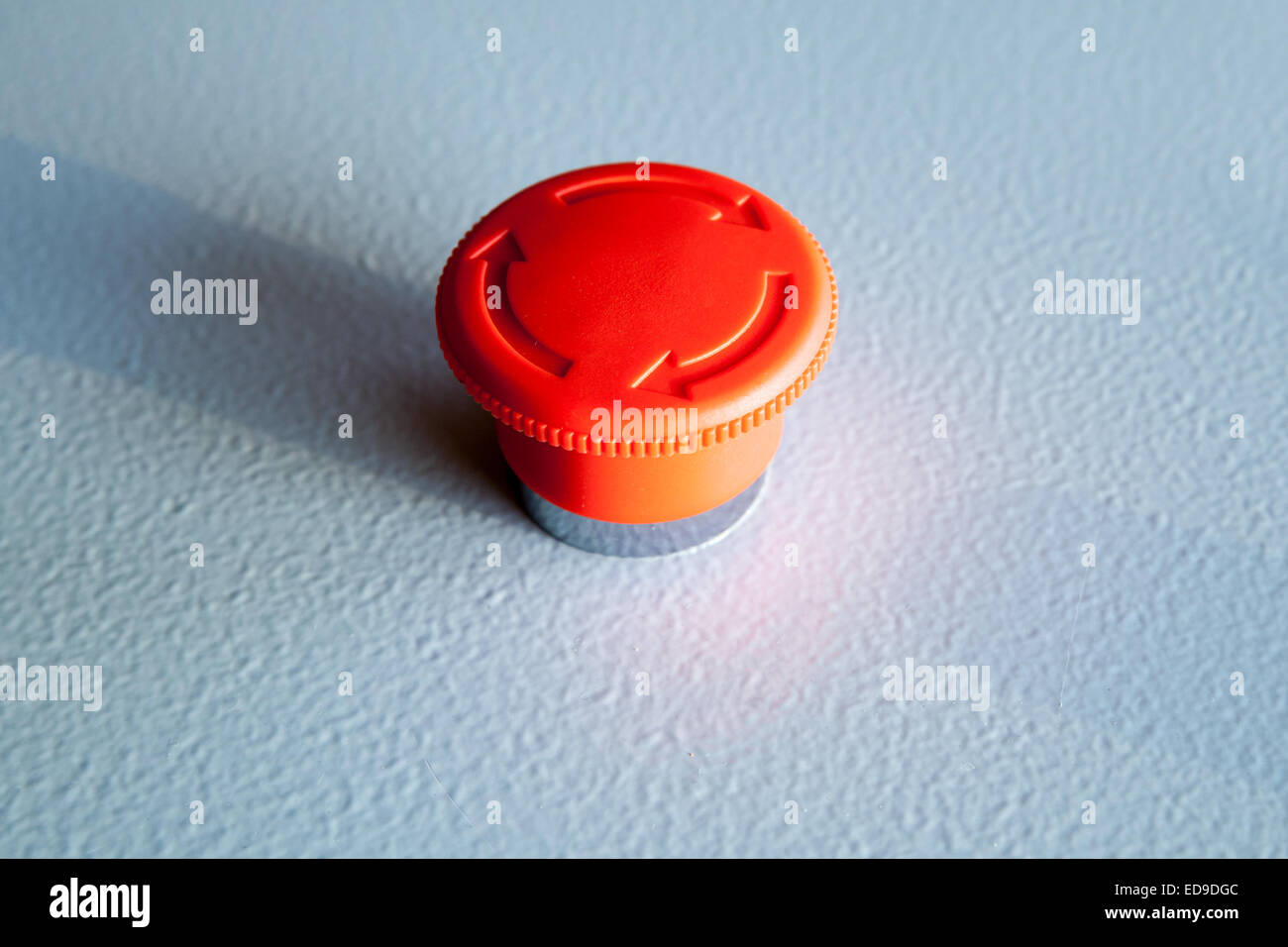 Red emergency stop switch reset industrial button on blue steel panel Stock Photo