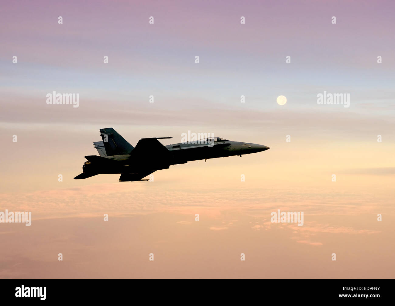 Navy F/A-18 jetfighter flying at high altitude before sunrise Stock Photo