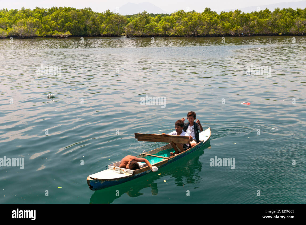 Indonesian children in a canoe in the waters of Wuring fishing village near Maumere on Flores island, Indonesia. Stock Photo
