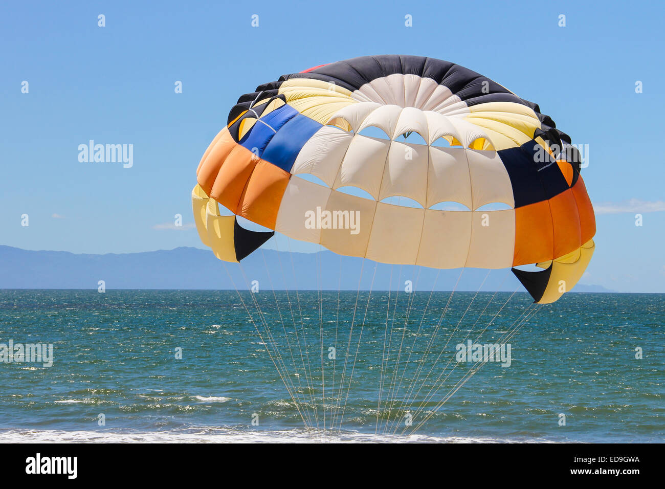 A bright colored parasail over the blue waters of the Pacific coast of Mexico on a warm sunny day Stock Photo
