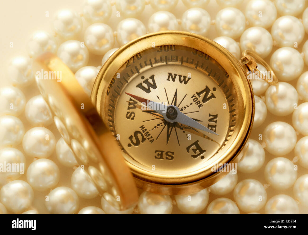 Golden compass on pearl necklace as background Stock Photo