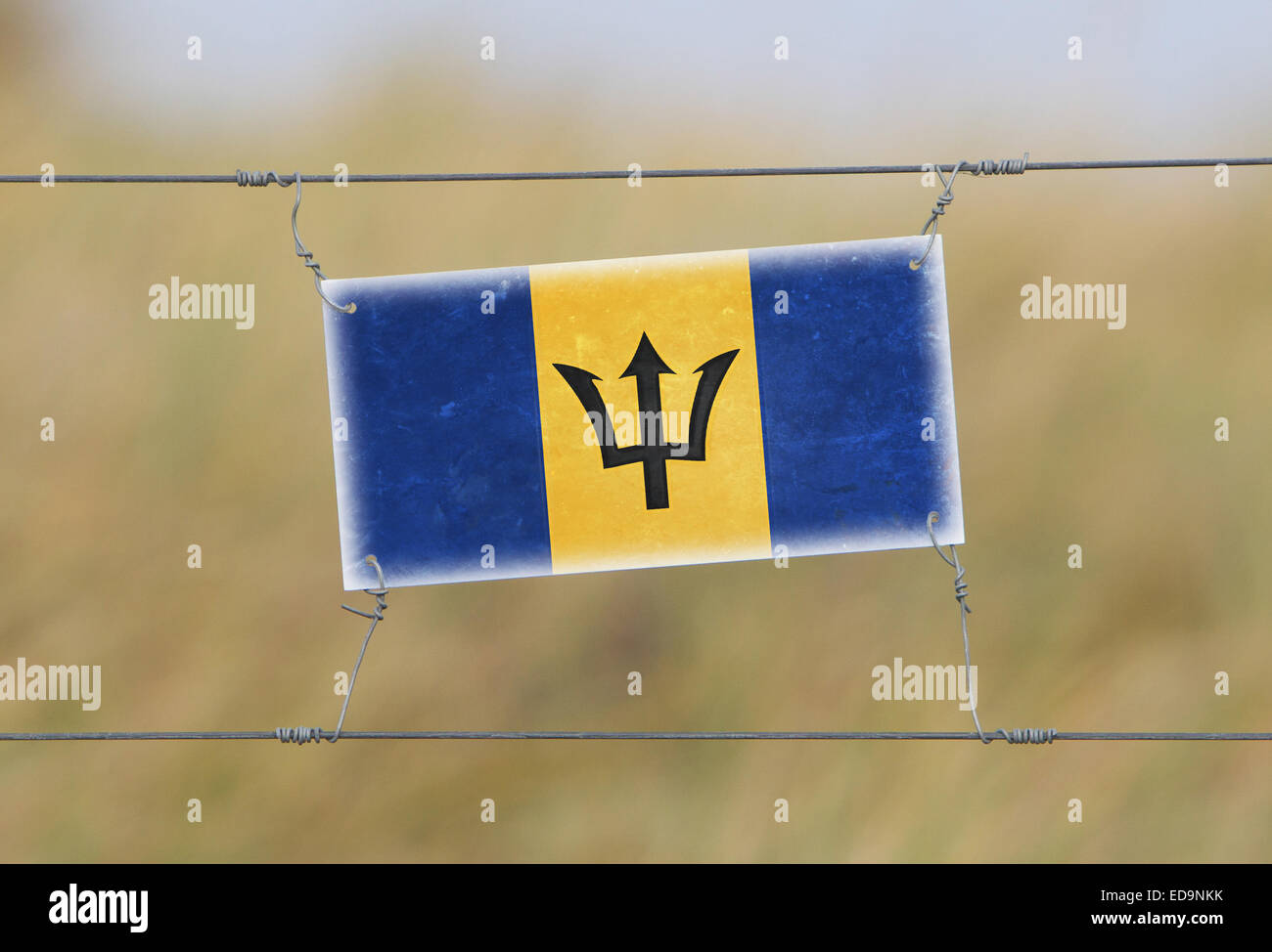 Border fence - Old plastic sign with a flag - Barbados Stock Photo