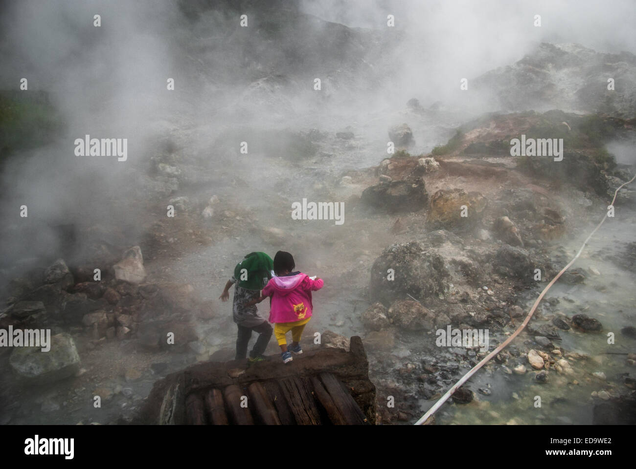 Children visitors are having recreational time on fumarole field at Bukit Kasih, a popular travel destination in Minahasa, North Sulawesi, Indonesia. Stock Photo