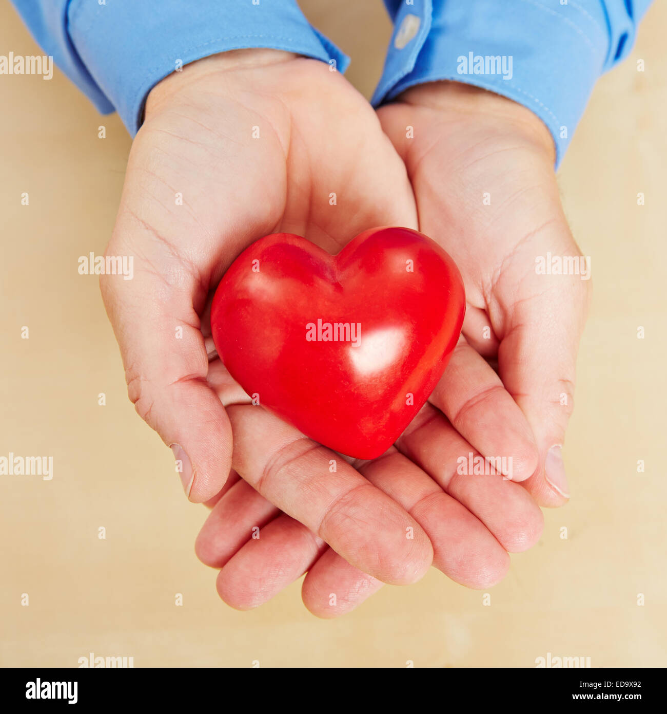 Man holding a red heart in his hands from above Stock Photo - Alamy