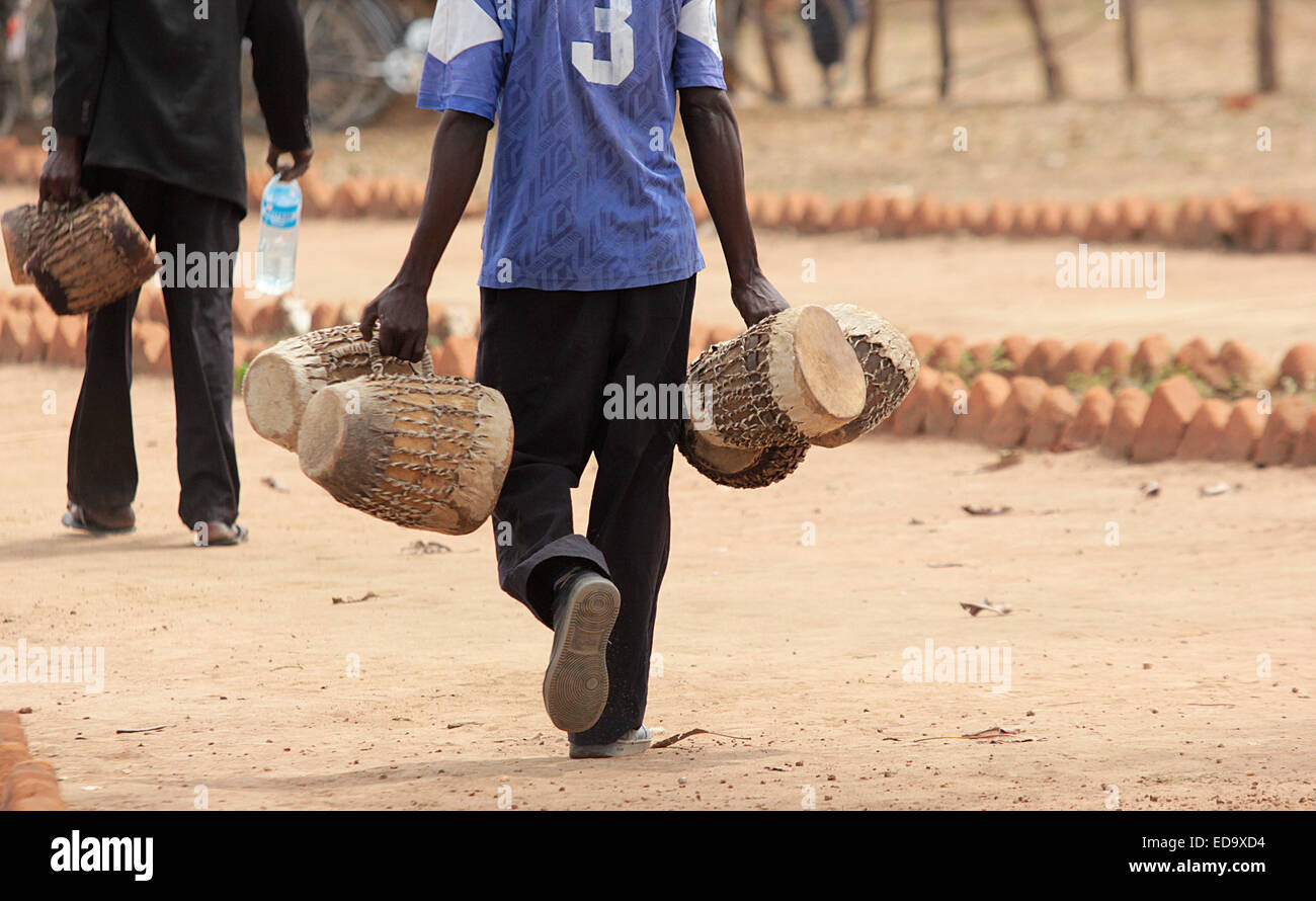 A traditional artists carries drums in northern Uganda. In africaq local music is used to pass on education messages against soc Stock Photo