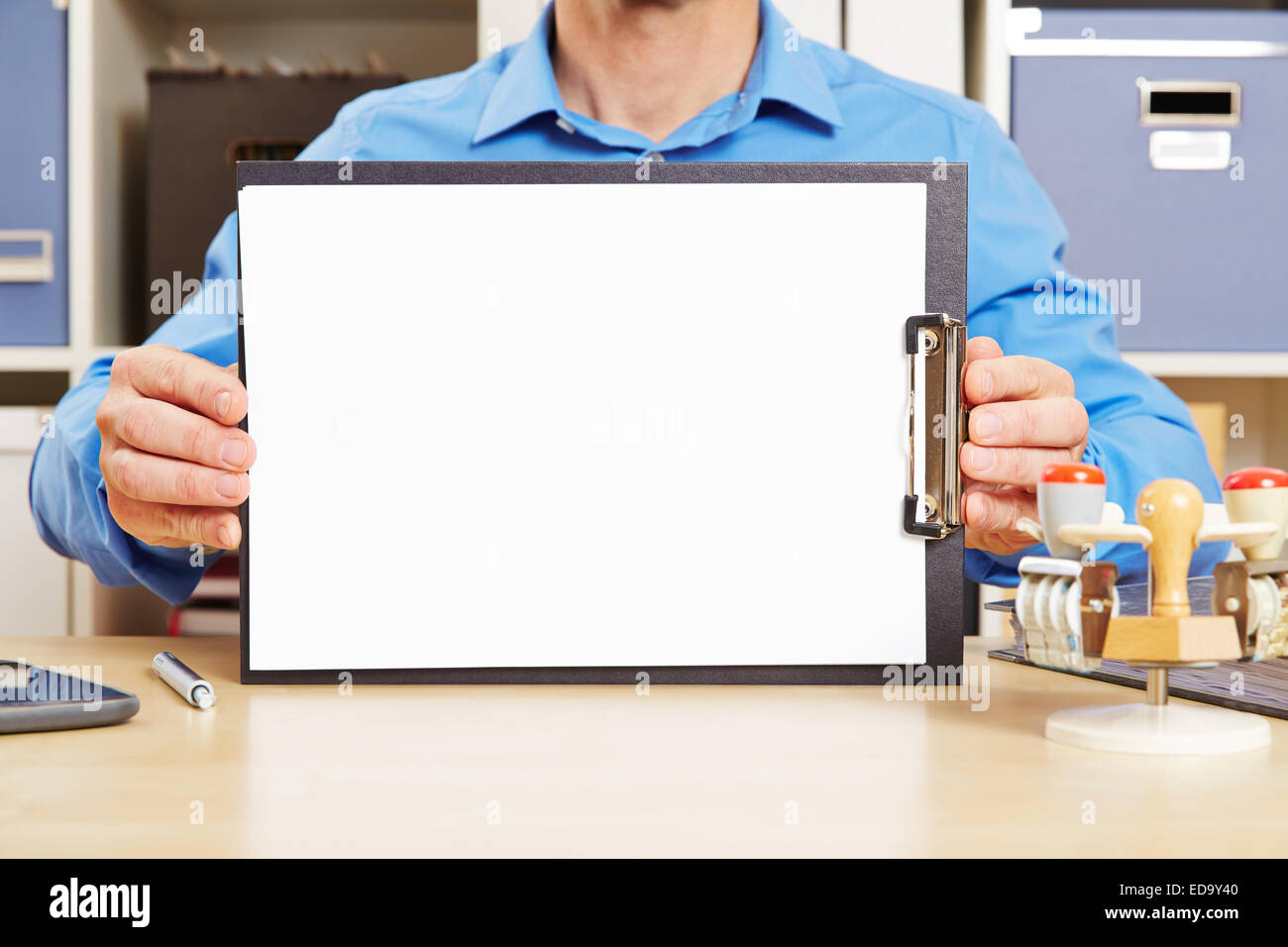 Man holding white sheet of paper on clipboard on an office desk Stock ...