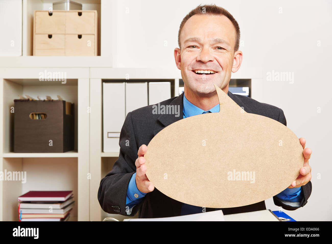 Happy business man in his office with an empty speech bubble Stock Photo