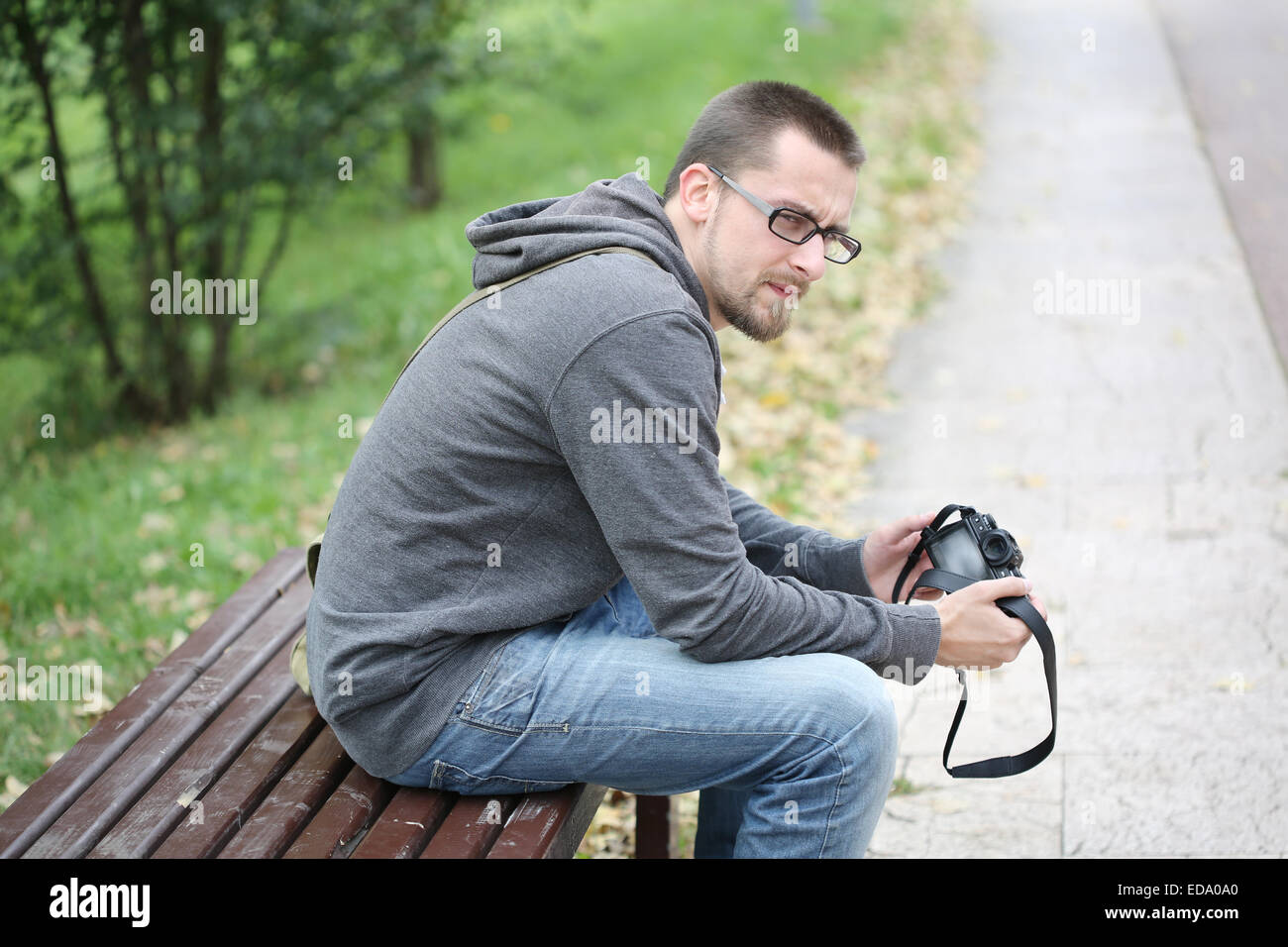 Young Man Sitting on a Bench in Park with Photo Camera Stock Photo