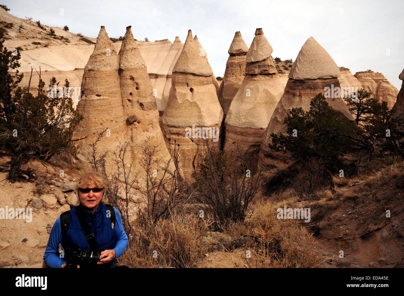 83 year old woman Hiking at Kasha-Katuwe Tent Rocks, Tents behind her. New Mexico - USA Stock Photo