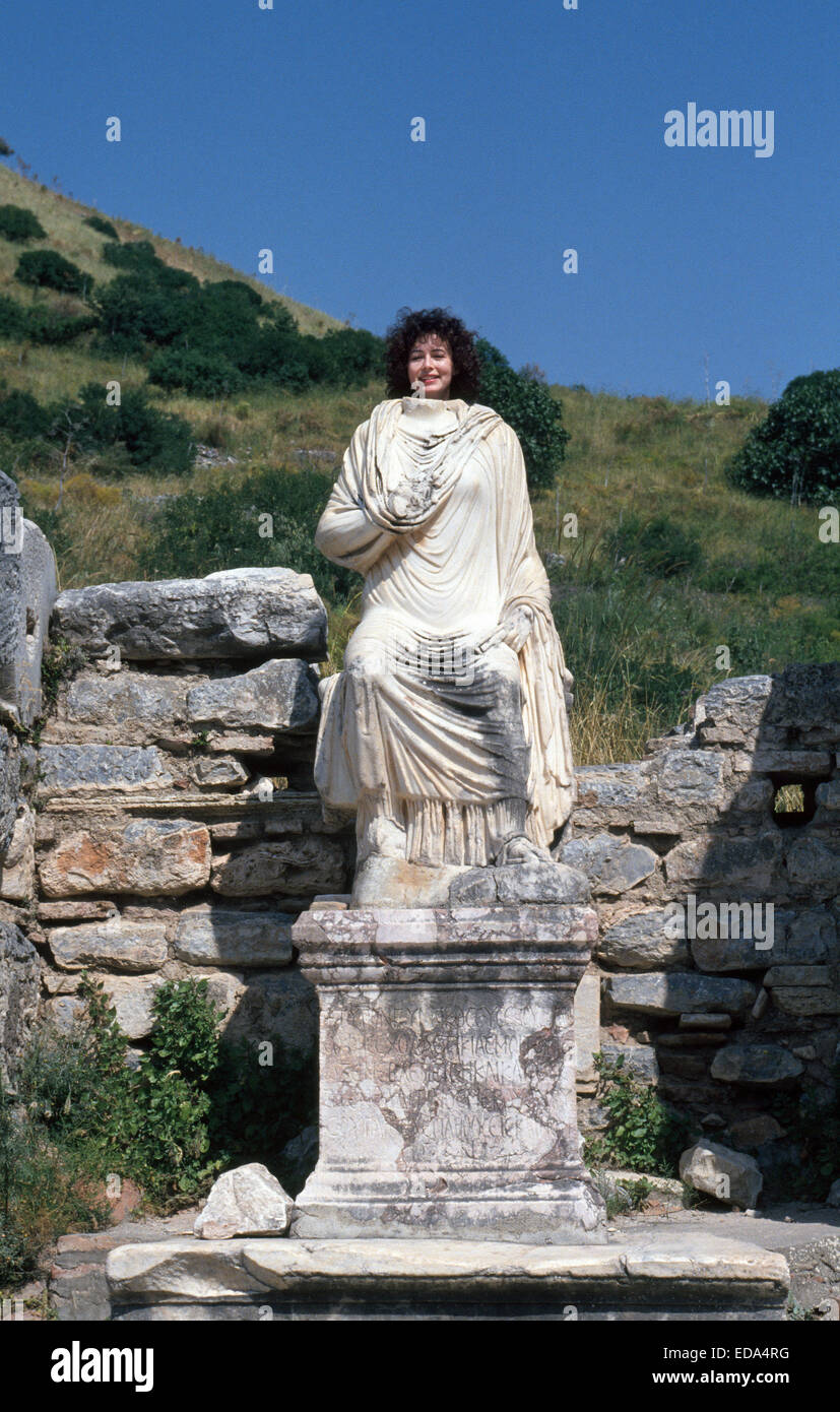 A tourist poses her head behind a decapitated statue amid the ancient Greek ruins at Ephesus in the Izmir Provence of Turkey along the Aegean coast. Stock Photo