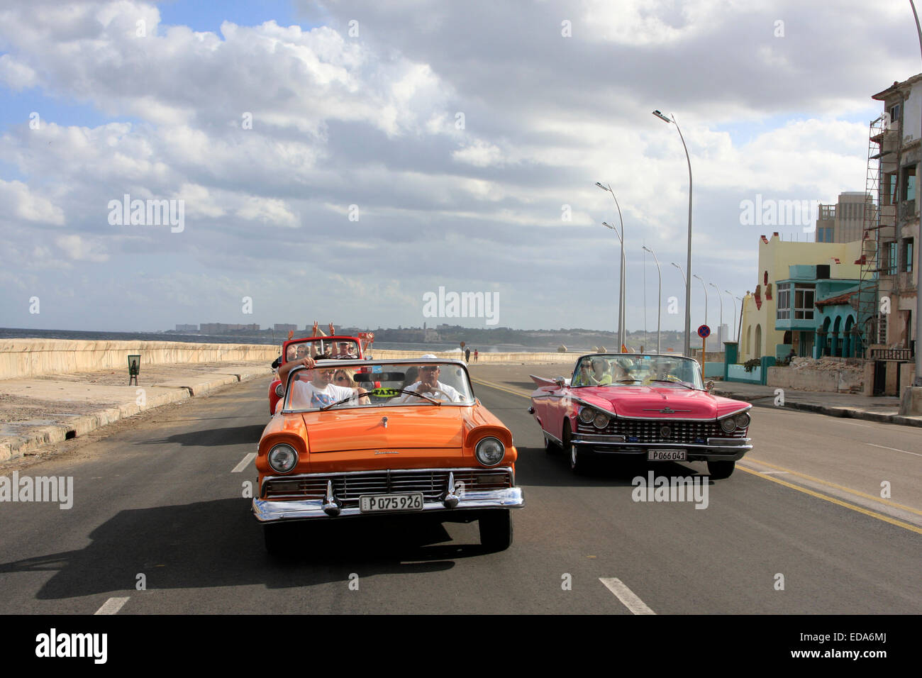 Tourists traveling in classic vintage convertible cars along Malecon in Havana, Cuba Stock Photo