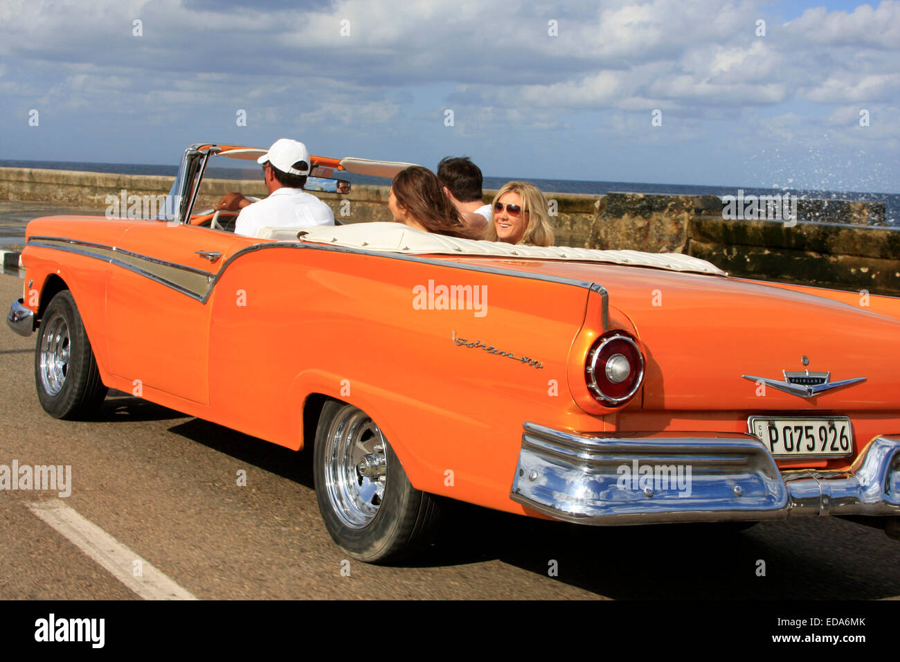 Tourists traveling in a classic vintage convertible car along Malecon in Havana, Cuba Stock Photo