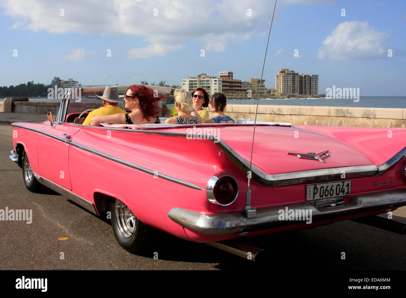 Tourists traveling in a classic vintage convertible car along Malecon in Havana, Cuba Stock Photo