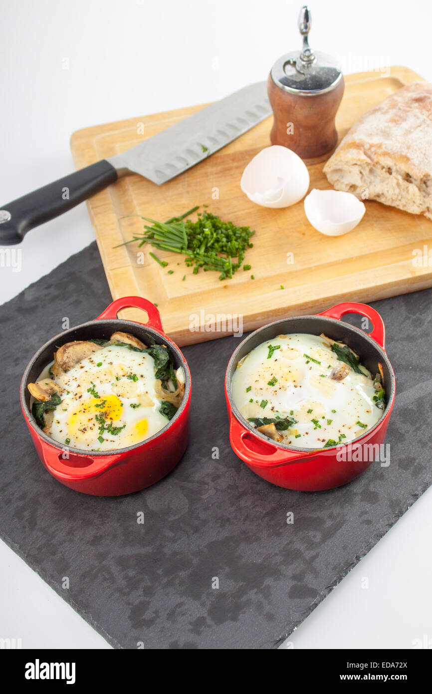 Baked Eggs in red Le Creuset croquettes on slate with garnishes and cutting  board background Stock Photo - Alamy