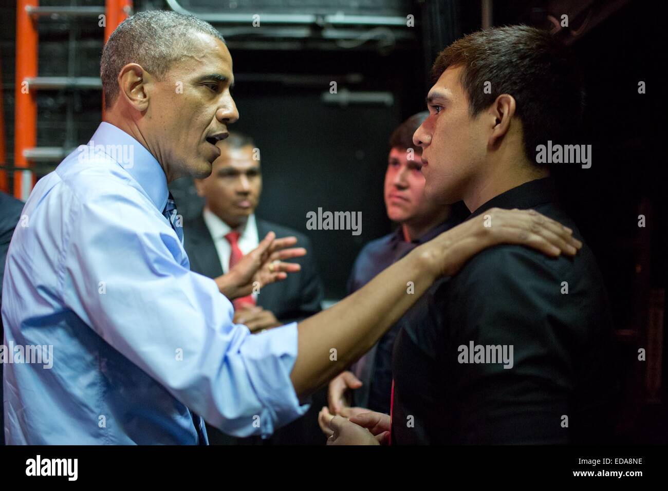 US President Barack Obama talks with two young men who heckled him during a speech on the economy July 10, 2014 in Austin, Texas. Obama spoke to the young men backstage to discuss their comments on immigration reform following their disruptions. Stock Photo