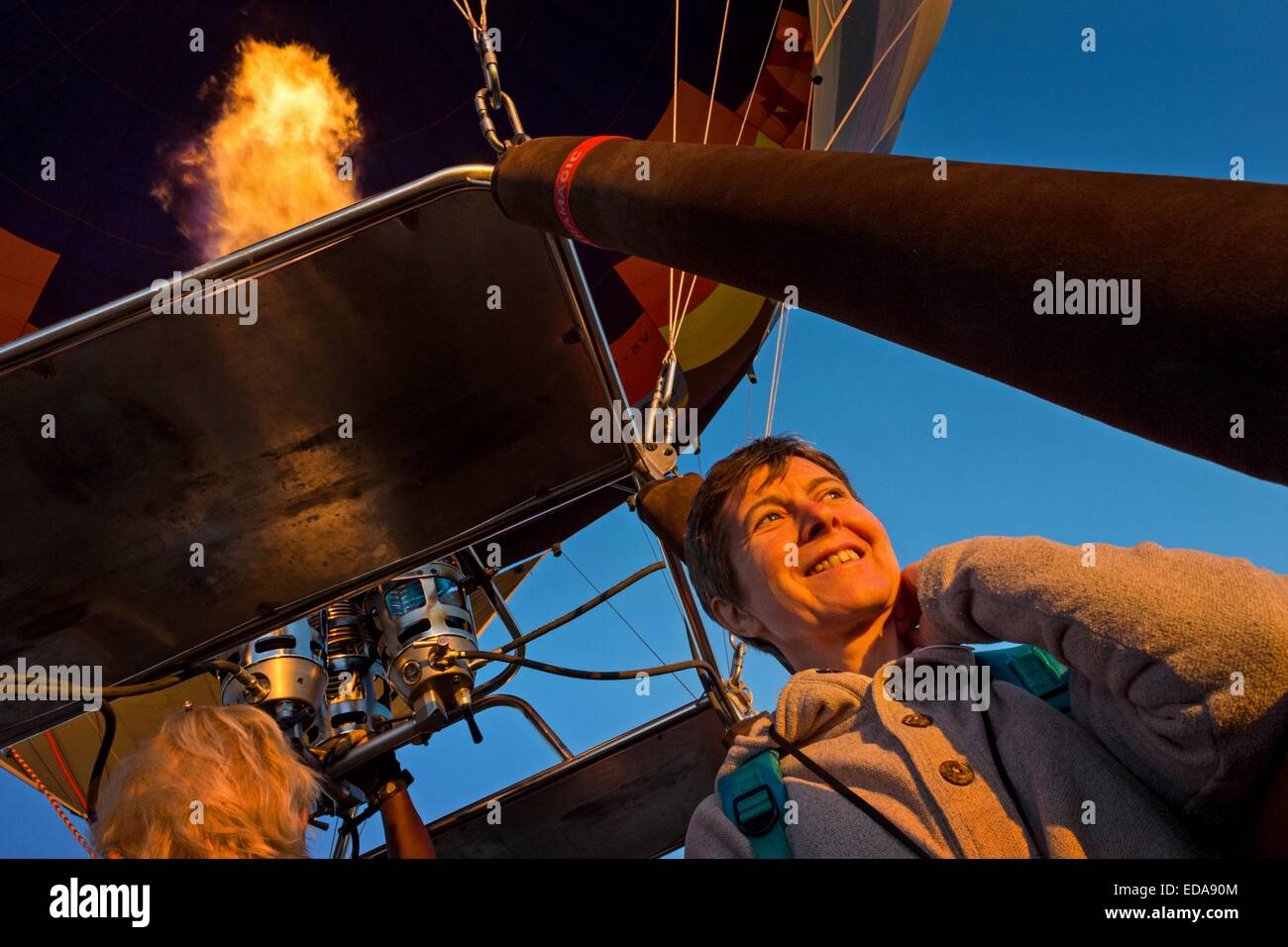 Woman smiling in early morning sunlight while enjoying a balloon flight over the desert in Namibia, Africa. Stock Photo