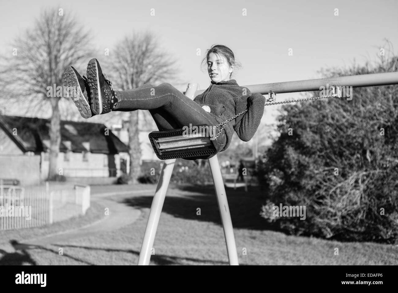Girl on a swing in a playground in Daventry, Northamptonshire during the winter Stock Photo