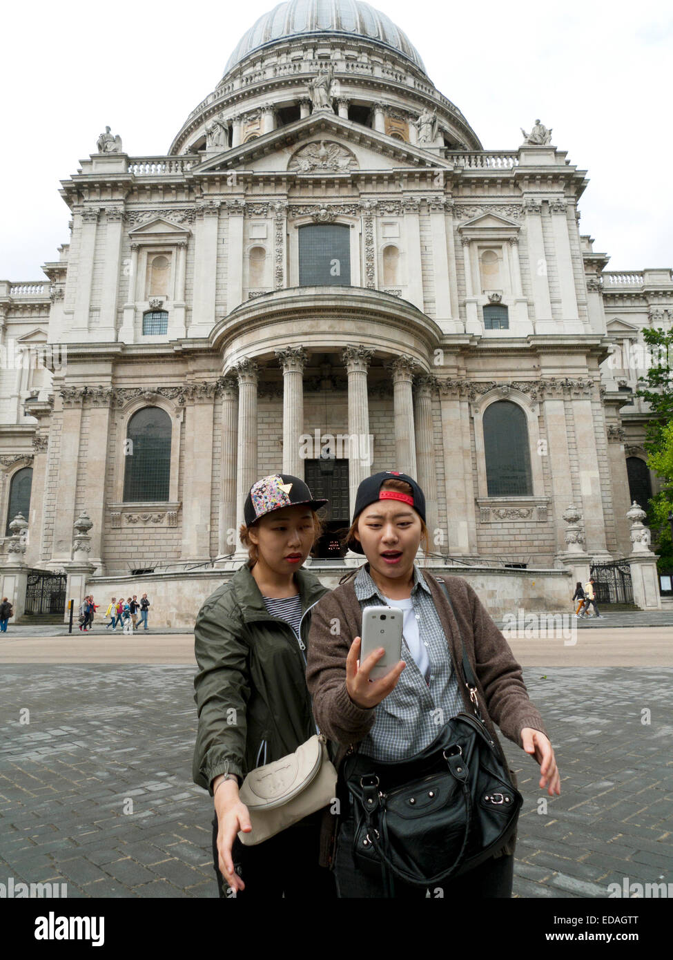 Two Asian Chinese girls tourists taking a selfie with a camera mobile phone outside St. Paul's Cathedral Central in London England UK KATHY DEWITT Stock Photo