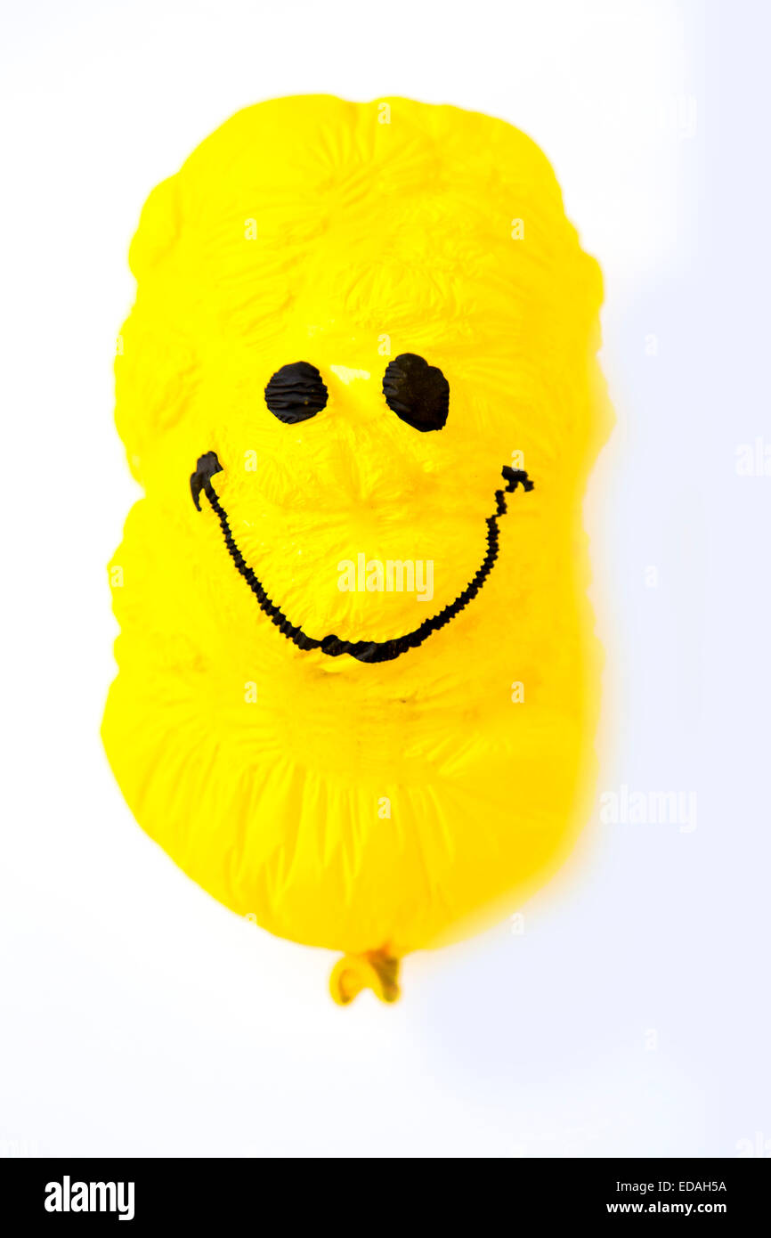 old Balloon, yellow, shriveled with friendly smiley face, sunken, wrinkled Stock Photo